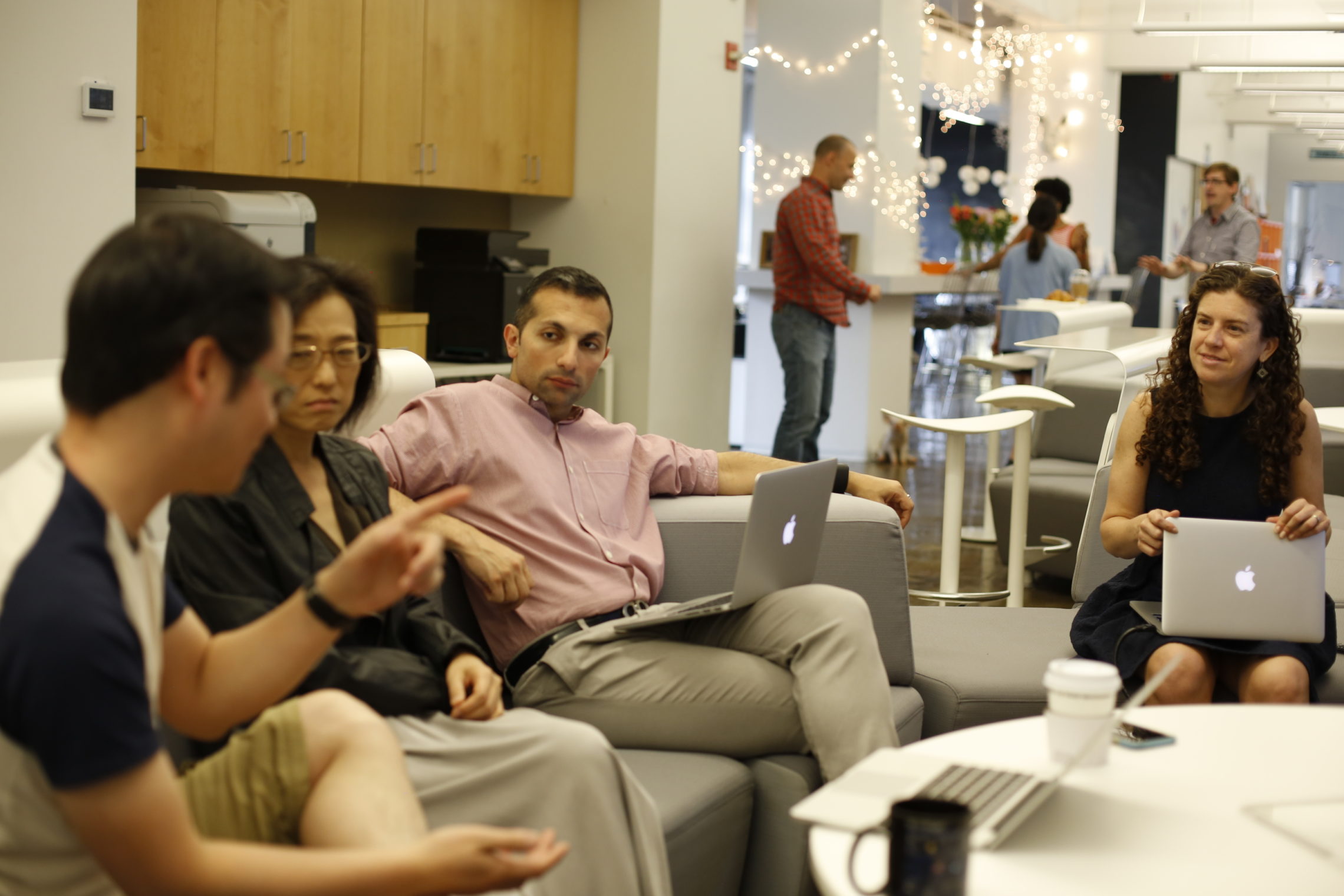 A group of people sitting at a table looking at a laptop