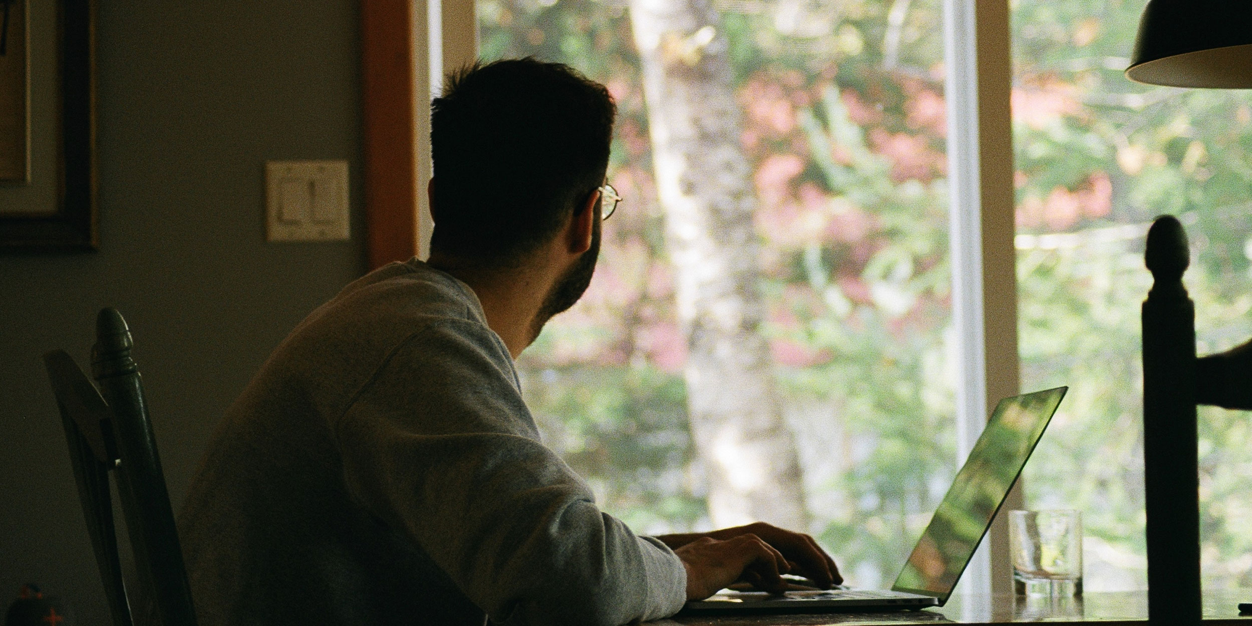 Gig worker at computer looking out window